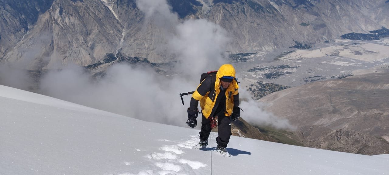 Climbing a steep snow slope above a valley