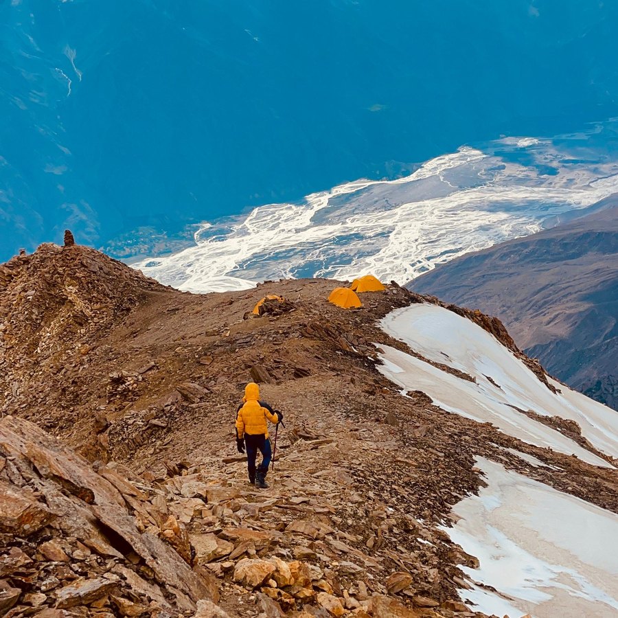Descending a scree ridge toward tents