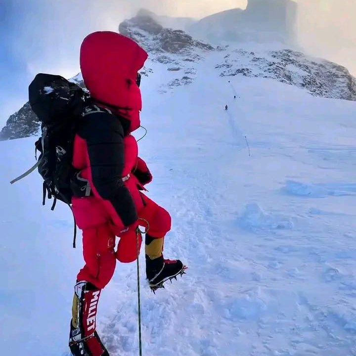 A climber in a red down suit on a fixed line in mist