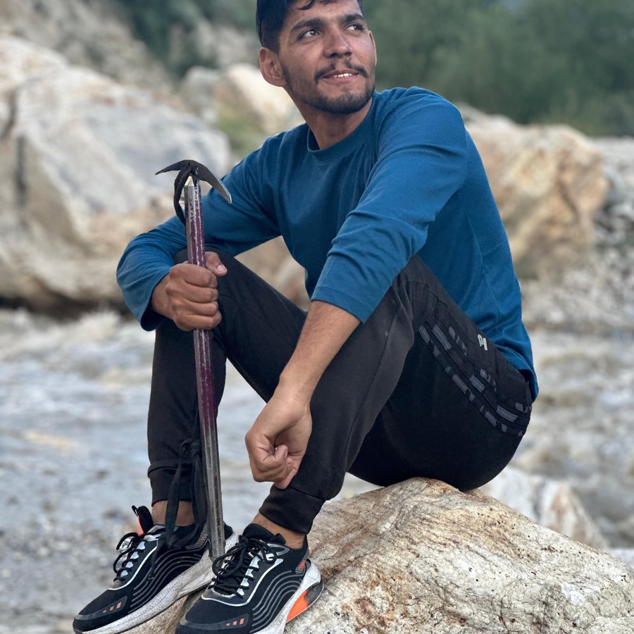 Fareed sitting on a boulder with an ice axe