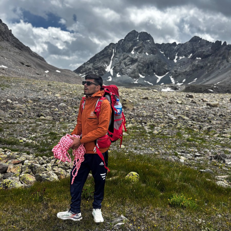 Coiling a climbing rope with a rocky peak behind