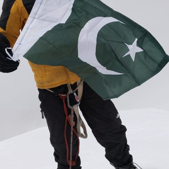 Holding the Pakistan flag on a misty summit